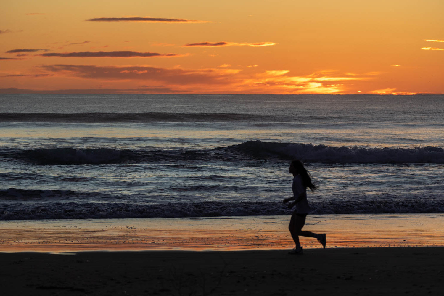 Person running along the beach at sunset, symbolizing health, wellness, and natural energy, as promoted by REGEN+